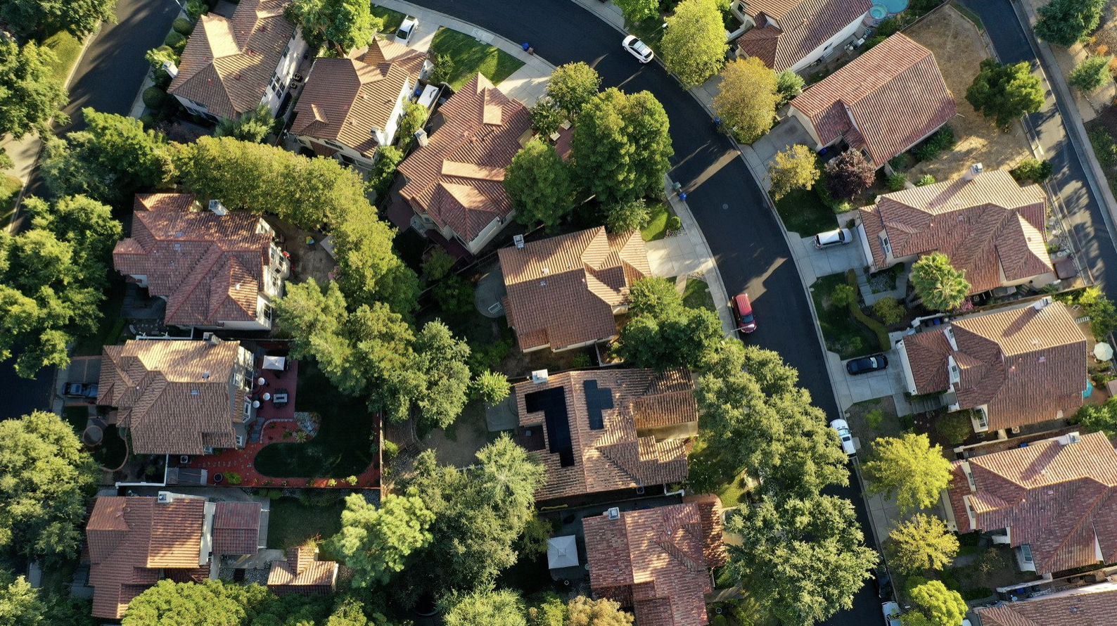 Neighborhood rooftops showing a house with rooftop solar panels